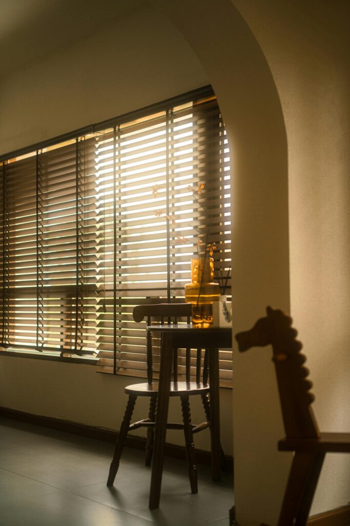 Warm interior scene featuring wooden blinds, chairs, and a table, creating a cozy atmosphere.