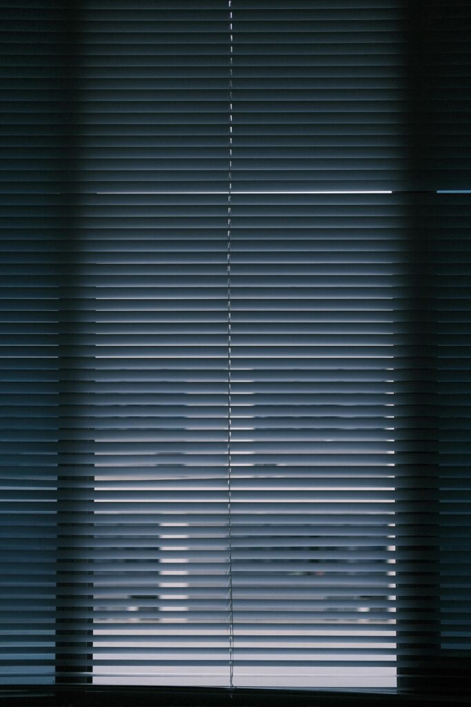 A vertical interior shot of closed window blinds creating a moody atmosphere.