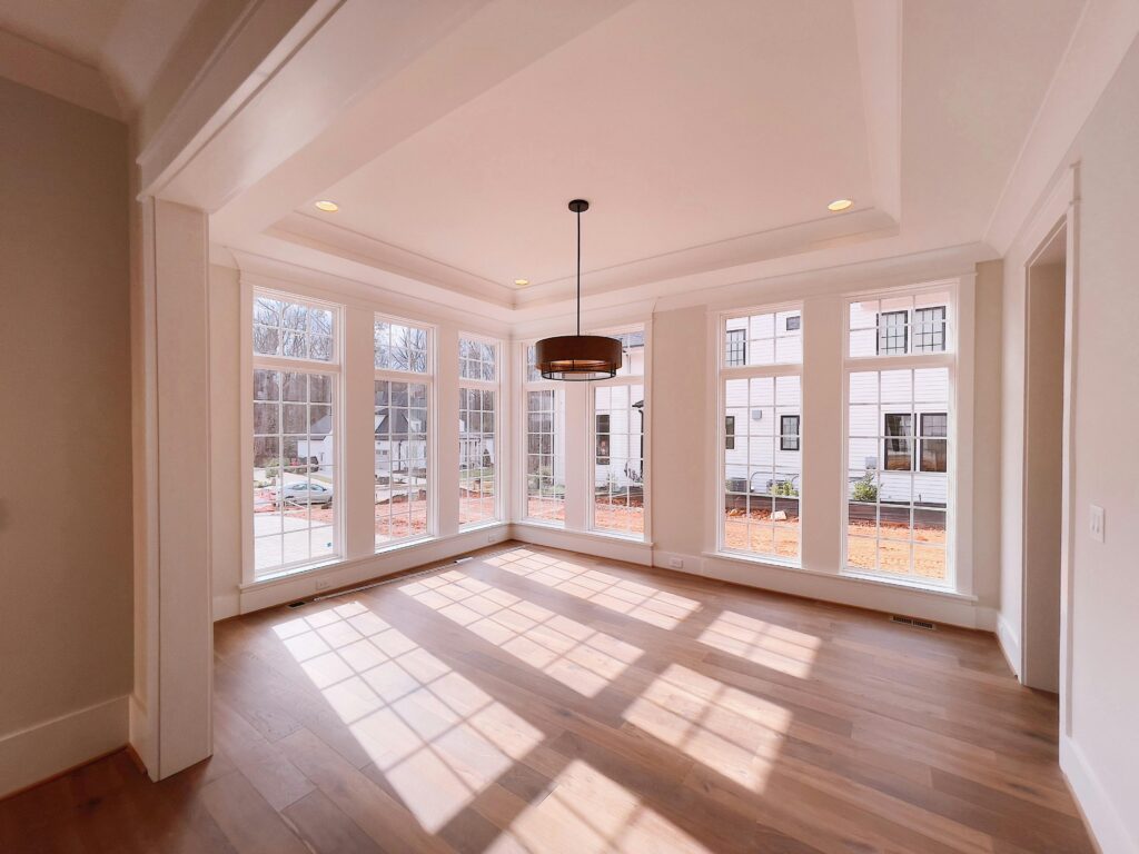Spacious indoor room featuring large windows, hardwood floor, and modern pendant lamp.